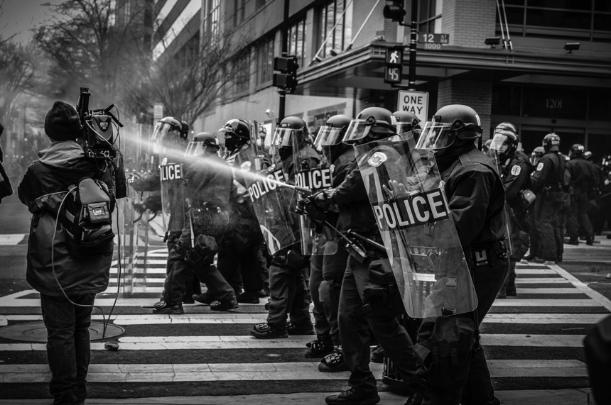 Line of policemen aiming a water cannon at demonstrators, Washington, USA.