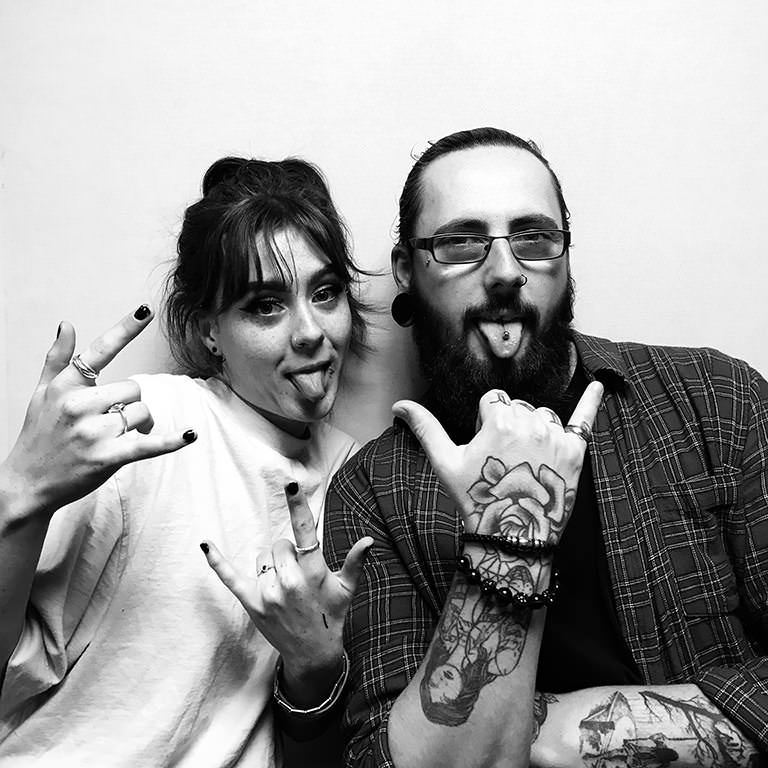 Black and white photograph of a woman and man sticking out their tongues.