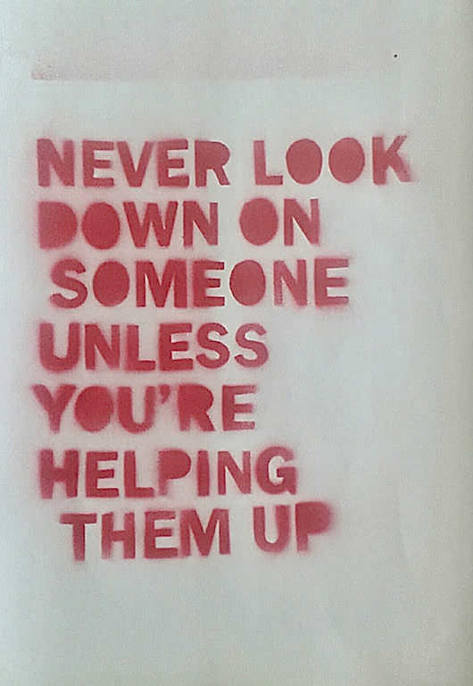 Red spray painted message that reads: Never look down on someone unless you're helping them up.