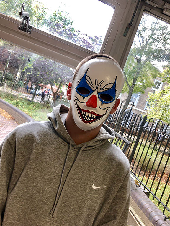 Photograph of a man wearing a joker style mask.